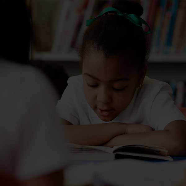 Young student reading a book in a classroom.