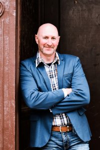 Man in blue blazer smiling confidently.